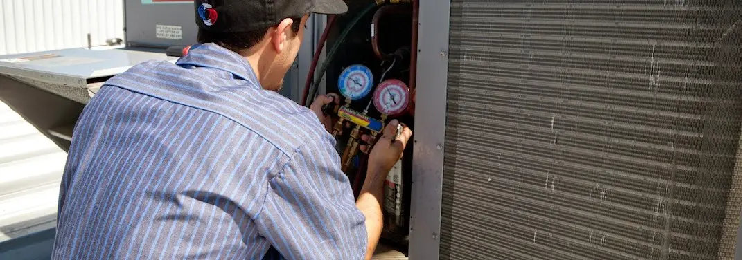 HVAC technician servicing a condenser unit in Robbinsville